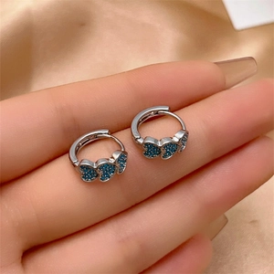 Macro view of silver hoop earrings featuring three sparkling blue heart-shaped zircons