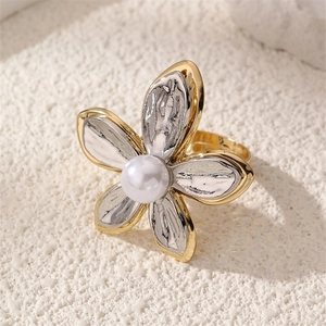 Macro detail of bicolor five-petal flower ring with central pearl on stone surface