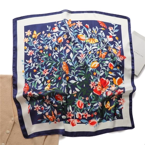 Detail plat neergelegd marineblauwe zijden sjaal met oranje vlinders en bloemenpatronen