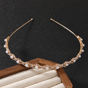Elegant gold headband with pearls and rhinestones on a display stand, minimalist design