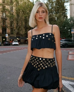 Détail d'un ensemble deux pièces noir avec des sequins dorés sur le haut et la jupe