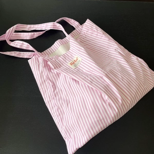 Dettaglio della borsa tote in cotone a righe rosa con etichetta tessuta Bébé su legno