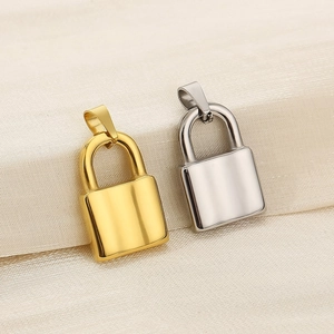 Close-up of polished gold and silver lock pendants on soft white silk fabric background