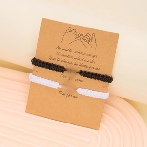 Close-up of black and white woven spider web bracelets on sentimental quote card