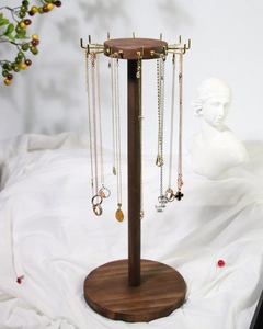Detail of walnut wood necklace stand with metal hooks on white silk background