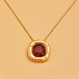 Macro shot of 18K gold plated square necklace with red zircon stone and radial engraving