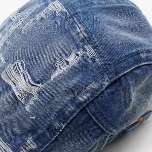 Dettaglio del berretto in denim blu con fori vintage e cuciture a doppia fila