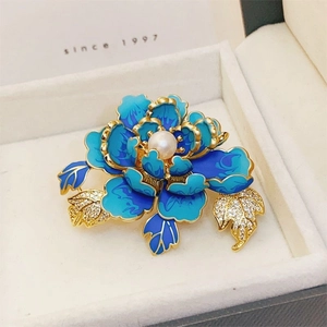 Elegante broche de flor dorada con esmalte azul degradado y perla central