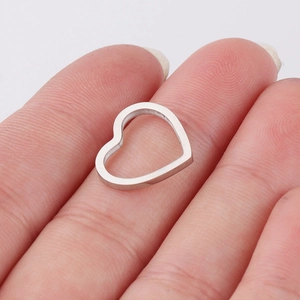 Close-up of a silver hollow heart-shaped titanium steel pendant held between fingers