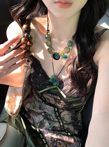 Detail of vintage layered necklace featuring green butterfly and coin pendant on neck