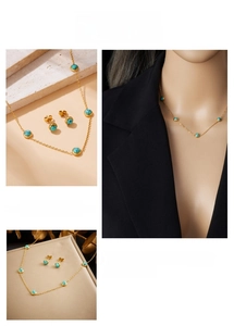 Detail of gold chain necklace and stud earrings set with turquoise beads on stone background