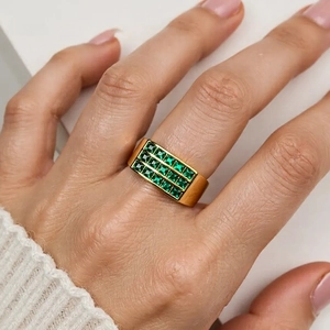 Close-up of a 18K gold plated ring with emerald green square zircons on a model's finger