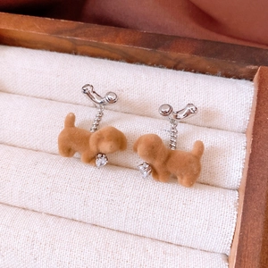Detail of flocking puppy earrings with zircon heart drop on beige linen jewelry box