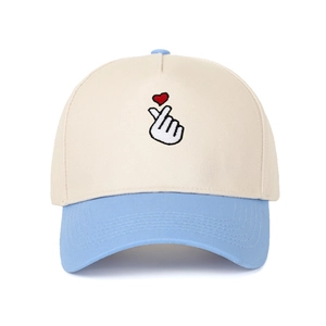 Detailed embroidery of a finger heart gesture on a beige and blue baseball cap