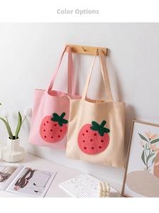 Detail of pink and beige canvas tote bags with 3D strawberry embroidery on wooden hooks