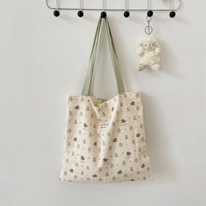Close-up of seersucker tote bag fabric with cute animal prints and green straps