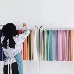 Chiffon pearl scarves displayed in a rainbow of colors hanging on black hangers