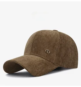 Détail de la casquette marron foncé en tissu à chevrons avec logo métallique latéral