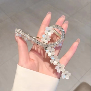 Detailed macro view of a silver flower hair claw clip with rhinestones and white petals