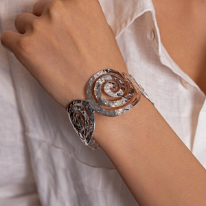 Détail du bracelet ouvert en spirale argentée avec texture martelée faite à la main