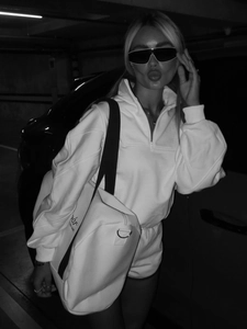 Detail of white half-zip sweatshirt with athletic shorts and branded sport bag in contrast
