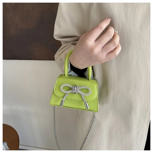 Detail of neon green mini bag with sparkling crystal bow and silver chain strap
