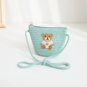 Detail of mint green straw crossbody bag with a cute bear patch and zipper for children