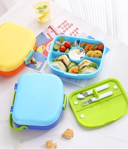 Close-up of five-compartment lunch box with stainless steel spoon and fork on a white desk