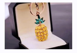Close-up of a rose gold pineapple keychain with yellow opal beads and green crystals