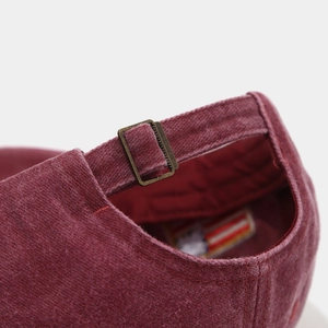 Macro view of burgundy vintage cotton cap featuring an adjustable bronze metal buckle