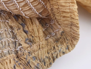 Detailed close-up of yellow smocked fabric texture with elastic white stitching detail