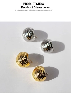 Detailed view of C-shaped earrings with vertical wavy brushed texture in gold and silver