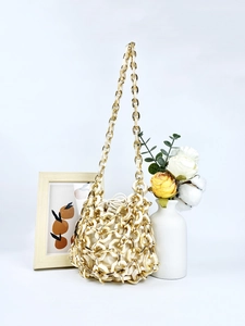 Detail of hand-woven acrylic rings with gold metal links and beige canvas drawstring bag
