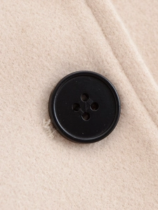 Macro shot of black four-hole buttons on beige woolen fabric for women short coat