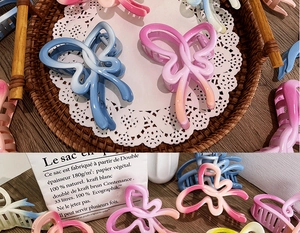 Close-up of gradient bow hair claws in various colors on a rustic tray and lace mat