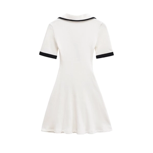 Dettaglio dell'abito in maglia bianca con scollo a V, colletto polo e bordi neri