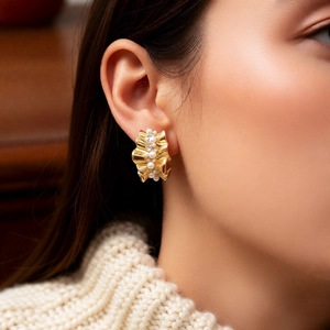 Detail of 14k gold plated C-shaped earrings with pearls on model in warm wooden light