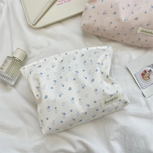 Close-up of floral cosmetic bags with blue flower patterns on soft fabric background