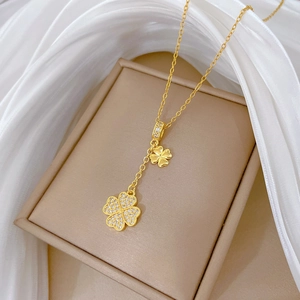 Luxurious gold four-leaf clover tassel necklace with sparkling diamonds on a silk background