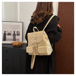 Rear view of a beige vintage college backpack worn by a model in a minimalist setting