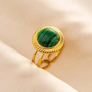 Detail eines verstellbaren Goldrings mit rundem Malachit auf cremefarbenem Seidenstoff