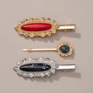 Detailed view of metal hair clips with turquoise and marble stones on a beige backdrop