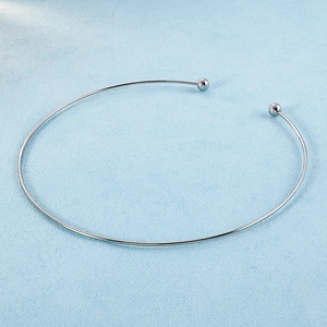 Macro detail of silver C-shaped titanium necklace with polished spherical decorative ends