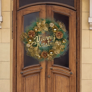 Golden Christmas wreath with pine needles and Merry Christmas sign on vintage wooden door