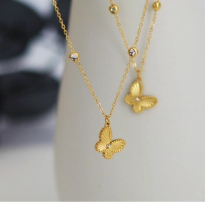 Detail of gold butterfly necklace featuring radial texture and fine zircon inlays