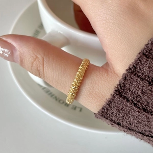 Macro detail of a 925 silver golden beaded ring worn on index finger in a lifestyle shot