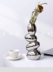 Close-up of pebble-shaped stacked silver vase with mirror finish and elegant dried flower decor