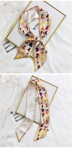 Detailed view of beige long silk ribbons with abstract portraits and golden lettering