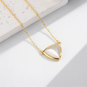 Minimalist gold necklace with triangle cat eye stone pendant on white stone