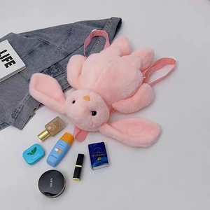 Pink plush rabbit backpack with long ears shown from above with cosmetic accessories
